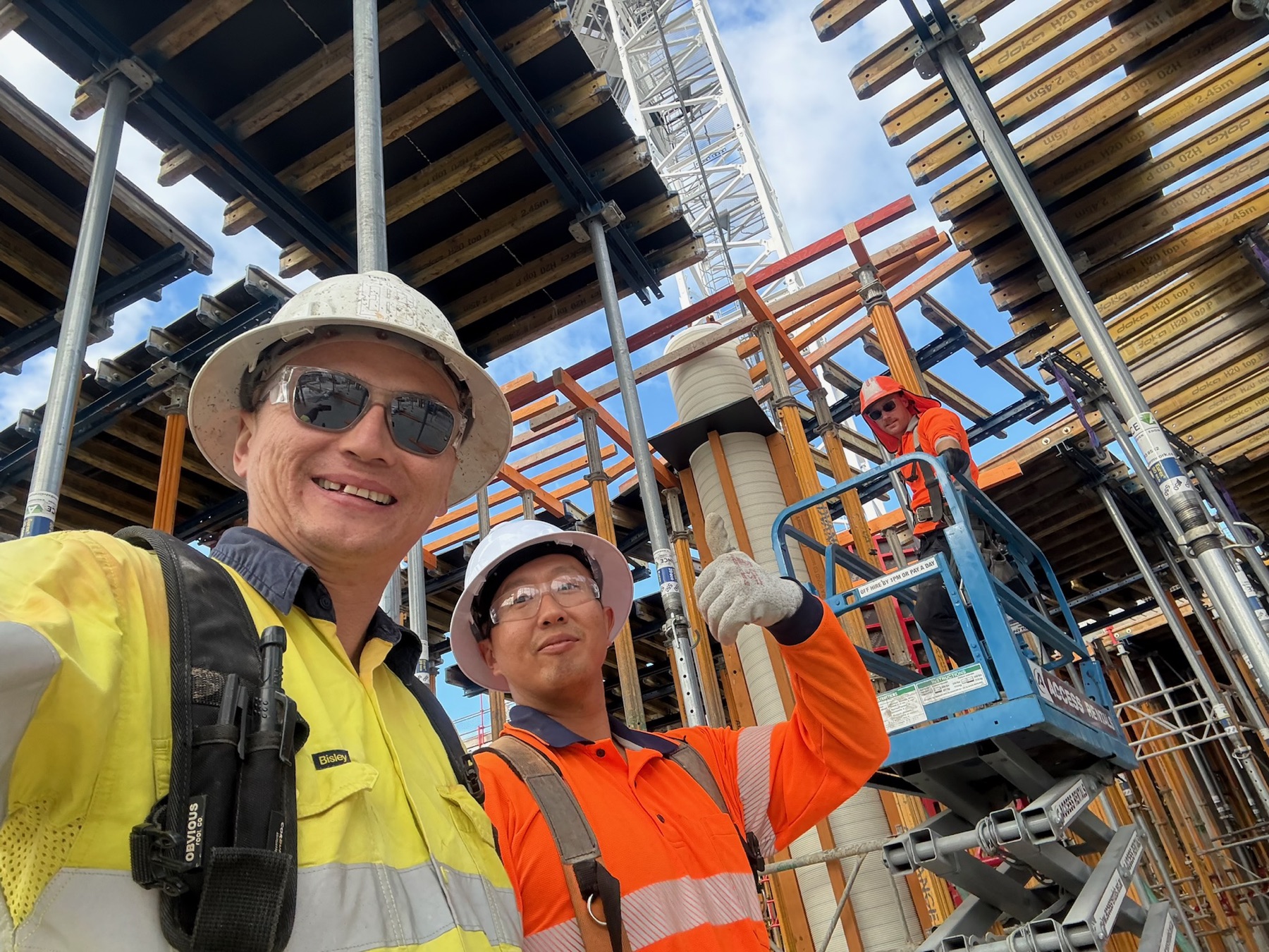 Togtuun workers in hard hats and high-visibility clothing beneath formwork on a high-rise construction site