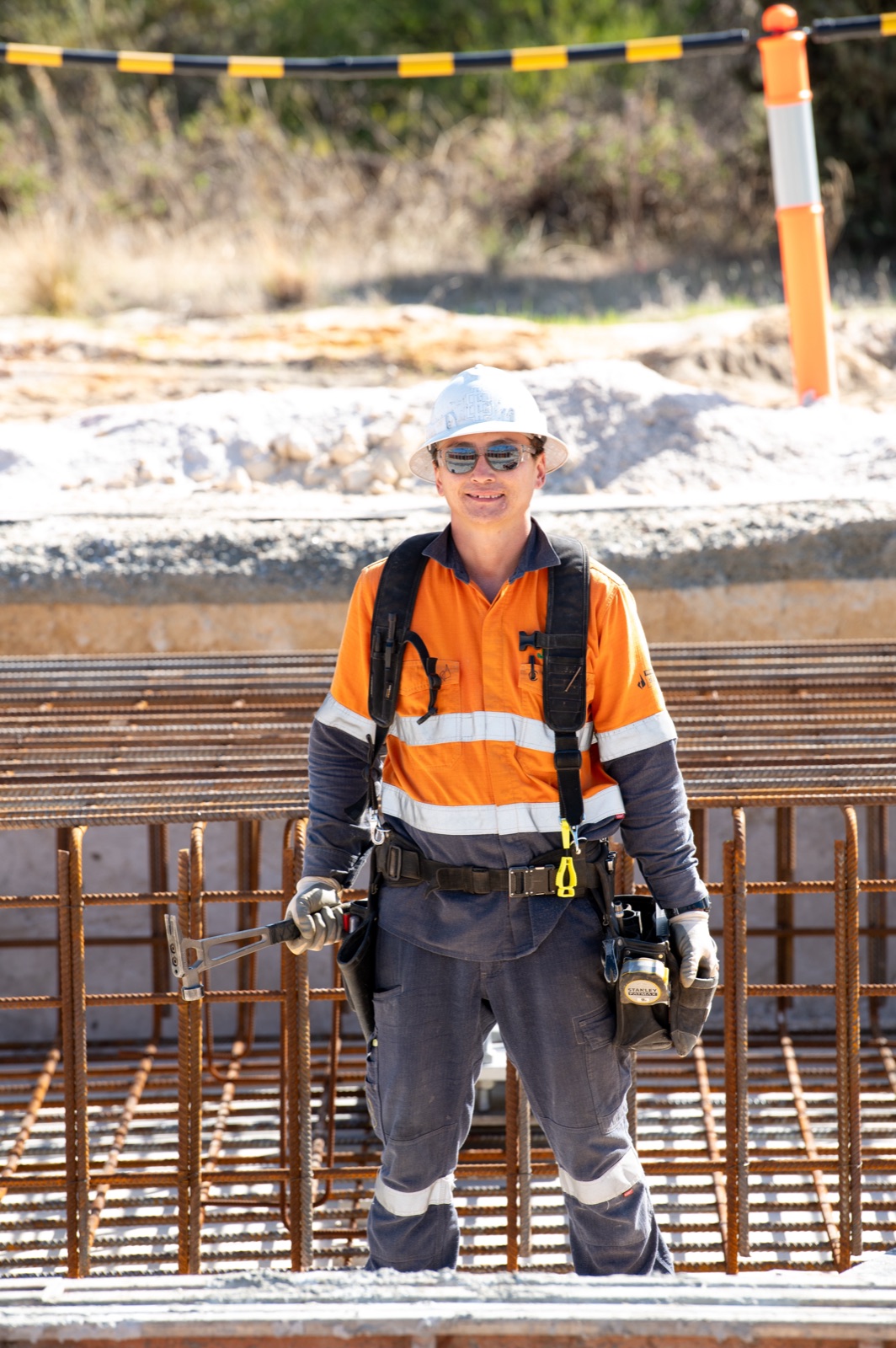 Togtuun crew member in full PPE — hard hat, safety glasses and high-visibility workwear — standing beside a reinforcement cage on site